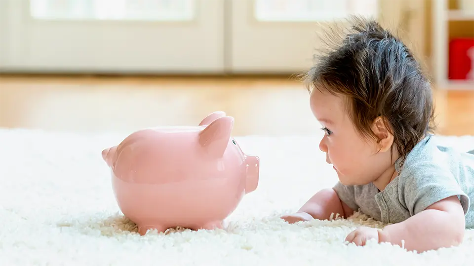 赤ちゃんと豚の貯金箱の写真